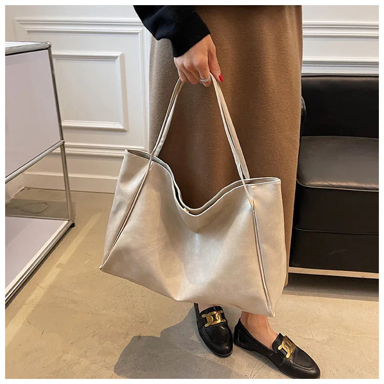Stylish beige tote bag for women, perfect for fashion and travel, paired with black loafers.